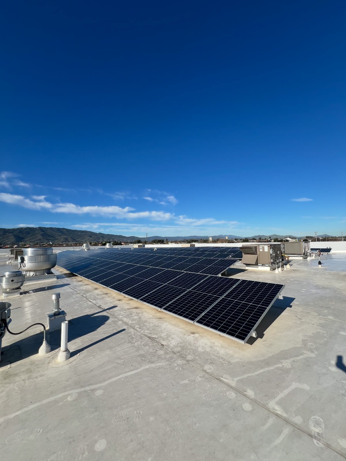 A South County solar array cleaned on a commercial rooftop, with the South County hills behind it