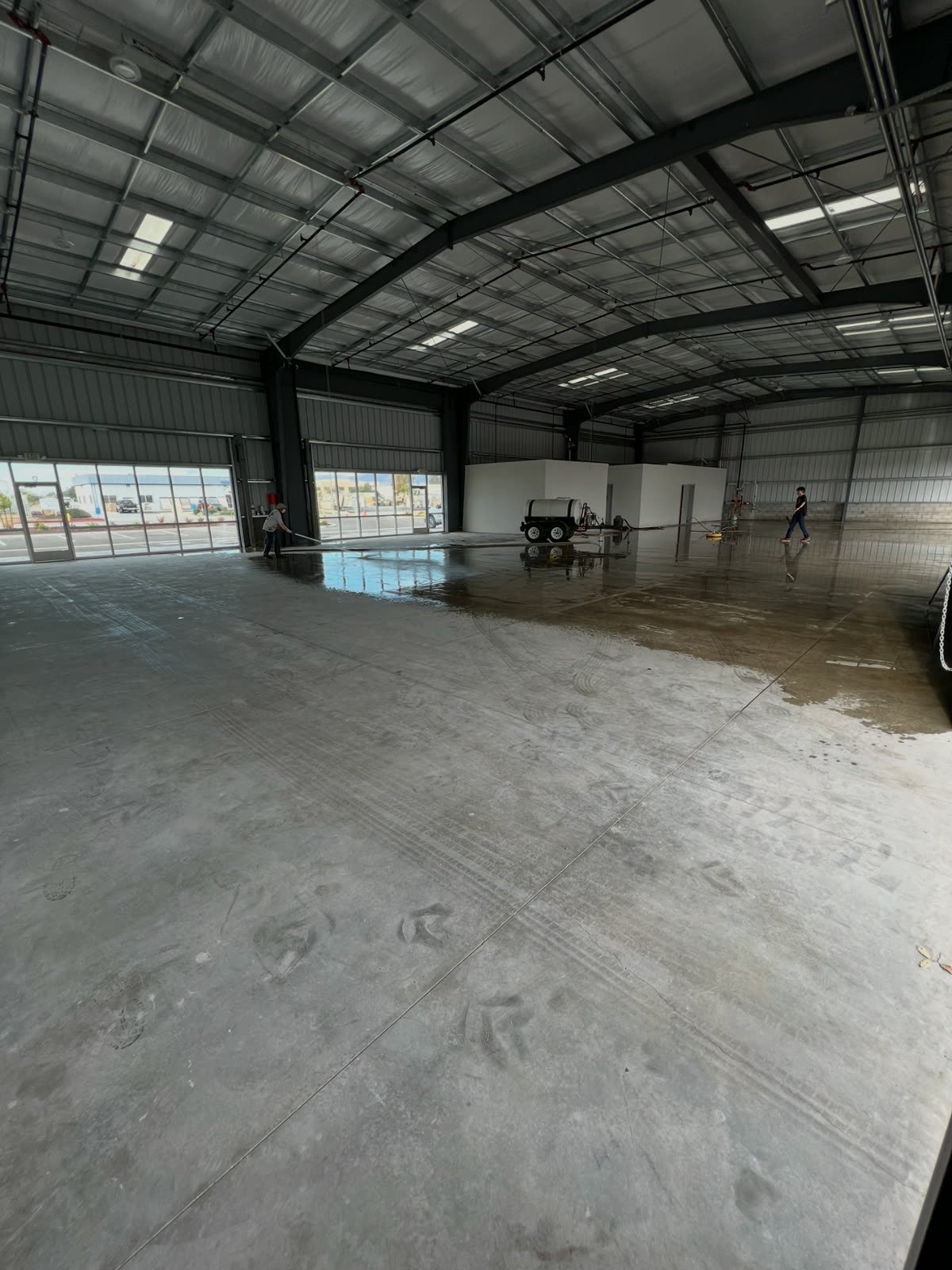 South County crew pressure washing the concrete floor of a large commercial warehouse