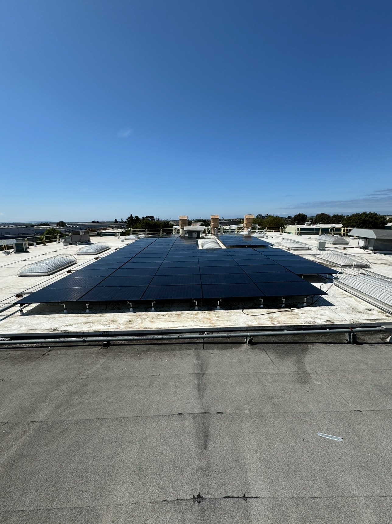 A freshly cleaned commercial rooftop solar array under a clear blue sky